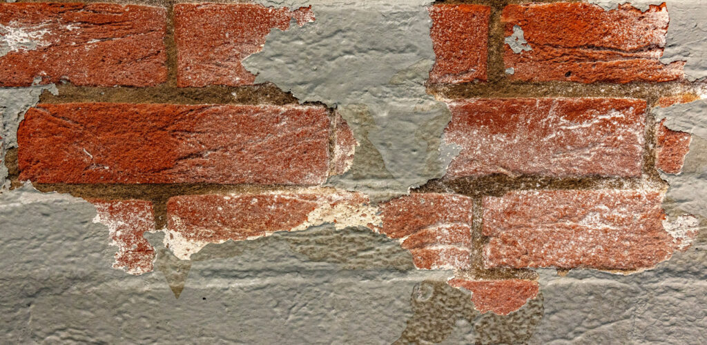 A closeup of paint peeling on a brick house