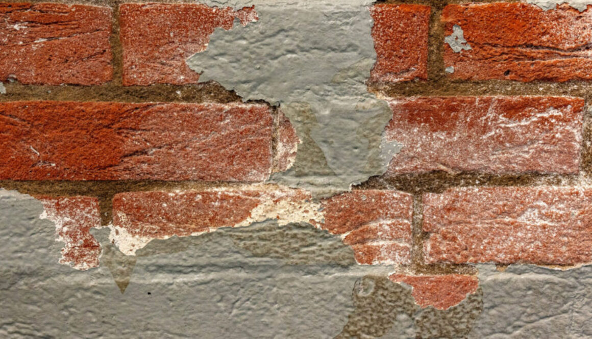 A closeup of paint peeling on a brick house