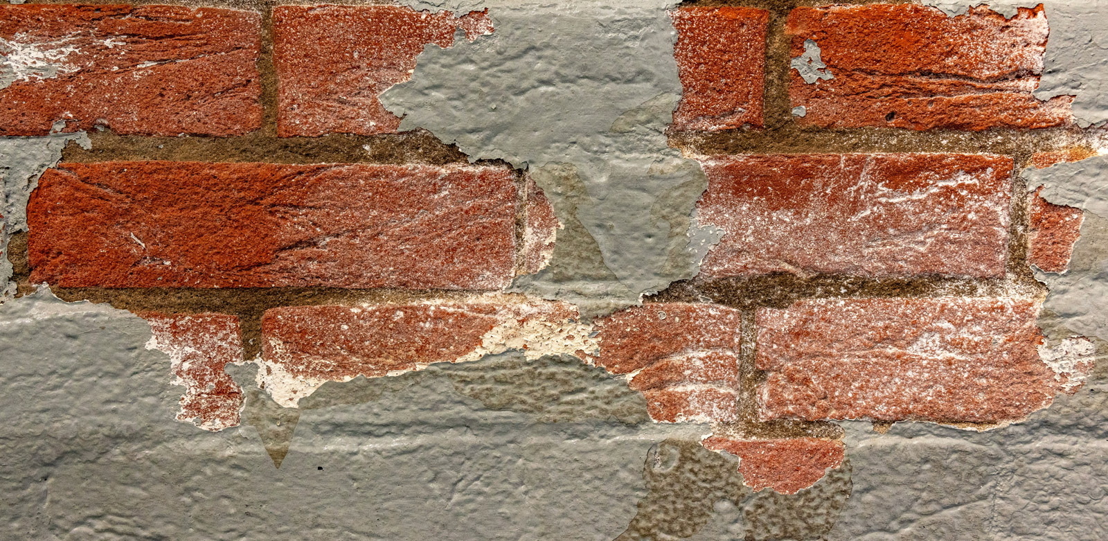 A closeup of paint peeling on a brick house